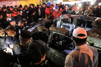 People, rescuers and security forces gather around a vehicle hit by a drone strike, reportedly killing three people, including two leaders of a pro-Iran group, in Baghdad on Wednesday.